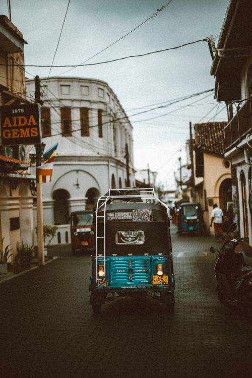 A traditional tuk tuk parked on a cobblestone street in historic Galle Fort, Sri Lanka, surrounded by colonial-era architecture